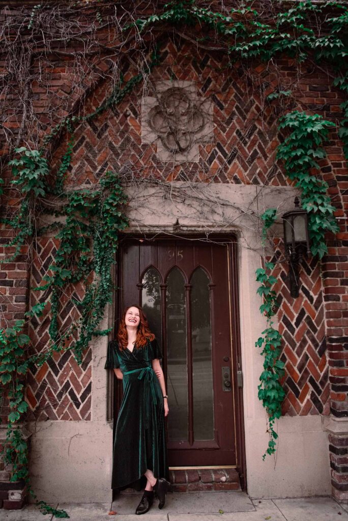 K.T. Jay standing in a doorway of an old brick building with vines growing on the walls.