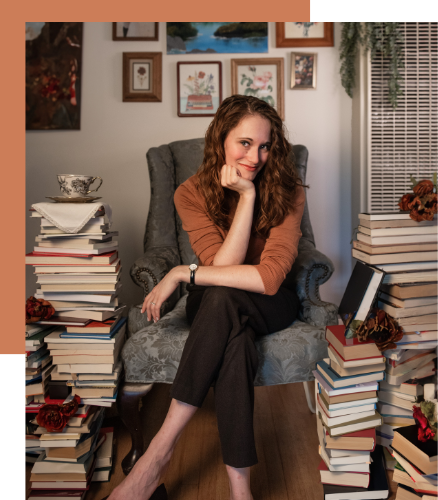 Fantasy fiction author K.T. Jay surrounded by stacks of books as she loves reading.