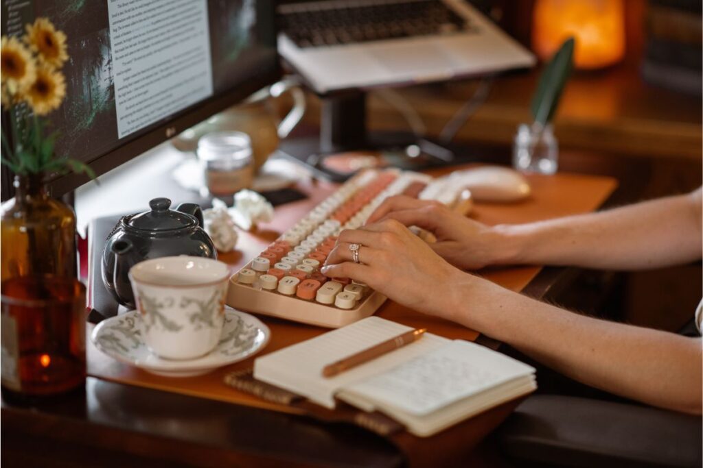 Author K.T. Jay following her writing system and typing an outline with her hand-written notes next to her. 